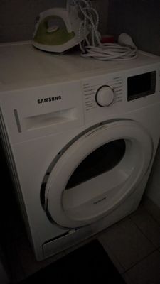 une machine à laver blanche posée dans un coin de la pièce