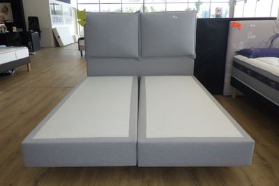 un lit sur lequel sont posés deux matelas, dans une chambre
