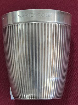 un vase en argent sur lequel est inscrit un nom, posé sur un tissu rouge