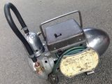 a small air compressor sitting on the ground next to a hose