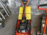 a red and yellow lawn mower sitting in a garage
