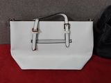 un sac à main blanc et un porte-monnaie noir sur un tapis rouge