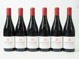 six bouteilles de vin rouge sont alignées sur une surface blanche
