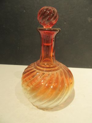 a red glass bottle with a swirly design on it