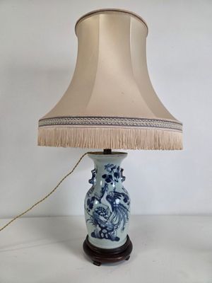 a blue and white lamp with a beige shade on it