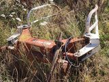 a rusted out tractor in the middle of a field