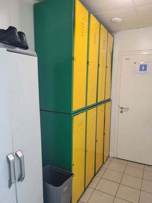 des casiers jaunes et verts dans un couloir, à côté d'un réfrigérateur blanc