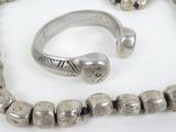 a silver bracelet and a silver ring on a white surface