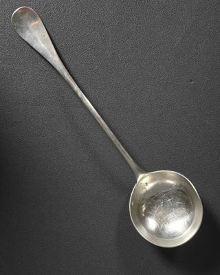 une cuillère en argent dont le manche repose sur une surface noire