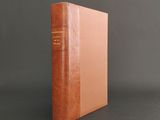 a brown book sitting on top of a table next to a gray wall