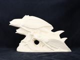 une sculpture en céramique blanche représentant un poisson sur une vague