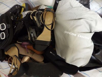 a pile of shoes and bags sitting on a bed