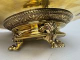 a gold bowl with a lion on it on a white surface
