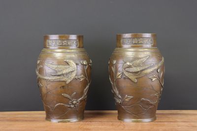 une paire de vases en bronze ornés d'oiseaux et de fleurs, posés sur une table