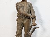 bronze statue of a man with a shovel on top of a table