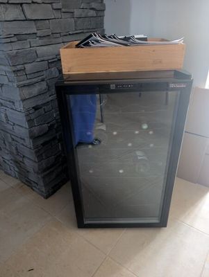 a small refrigerator sitting in front of a stone wall