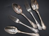 five silver spoons and a fork on a black surface