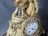 a gold clock with a statue on top of it