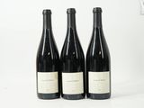 trois bouteilles de vin sont alignées sur une surface blanche