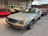 a silver car parked in a garage with other cars in the background
