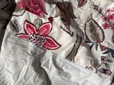 a close up of a bed with a white and red comforter on it
