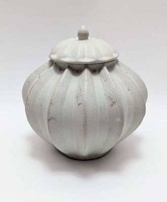 a white vase with a lid sitting on a white surface