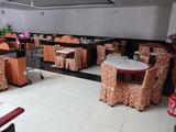 Dans un restaurant, les tables et les chaises sont alignées et recouvertes de nappes orange.