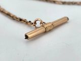 gold plated pen charm with chain on a white surface