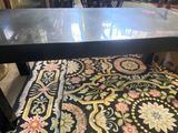 une table noire avec un plateau en verre posée sur un tapis