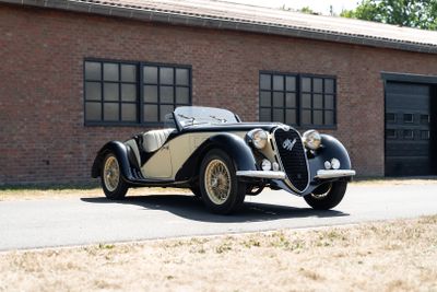 a black and white car parked in front of a brick building