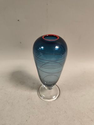 un vase bleu bordé de rouge posé sur une table
