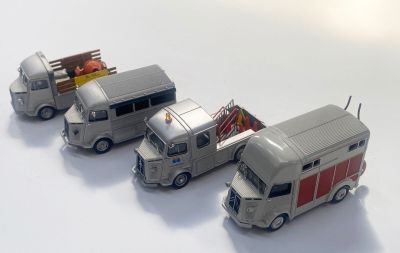 trois camions miniatures alignés sur une surface blanche