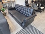 a black leather couch sitting in the middle of a living room