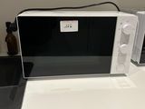 un micro-ondes blanc posé sur un plan de travail, à côté d'un téléphone portable
