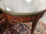 une table ancienne au plateau en marbre posée sur un tapis dans une pièce