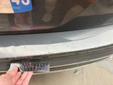 a person holding a sticker on the bumper of a car