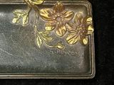 a gold plate with flowers on it on a black surface