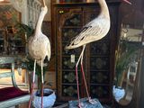 two statues of birds sitting on top of a glass table