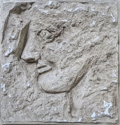 relief of a woman ' s face on a stone block