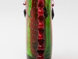 a green and red vase with red beads on it