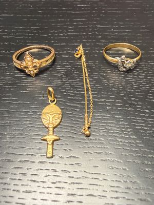 three gold rings and a necklace on a black surface