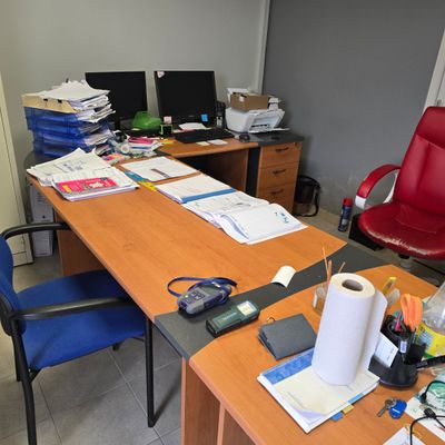 un bureau recouvert de papiers et une chaise rouge