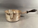 an old silver pot with a wooden handle sitting on top of a table