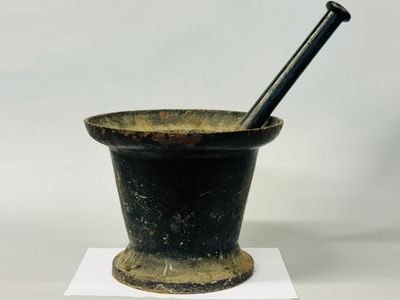 an old mortar with a pestula in it sitting on a white surface