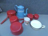 a blue teapot and red pots and pans on a table