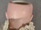 a pink vase with a lace around it on top of a table