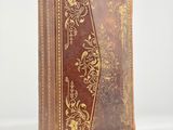 an old book with a brown cover and gold designs