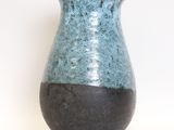 a blue and black vase sitting on a white surface