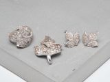 trois bijoux en argent posés sur une surface grise