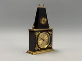 une horloge noire et dorée surmontée d'un soleil